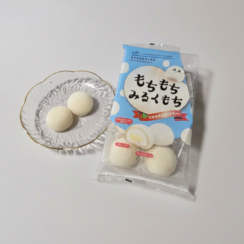 Packaged milk cream mochi with a clear glass plate holding two pieces of mochi.